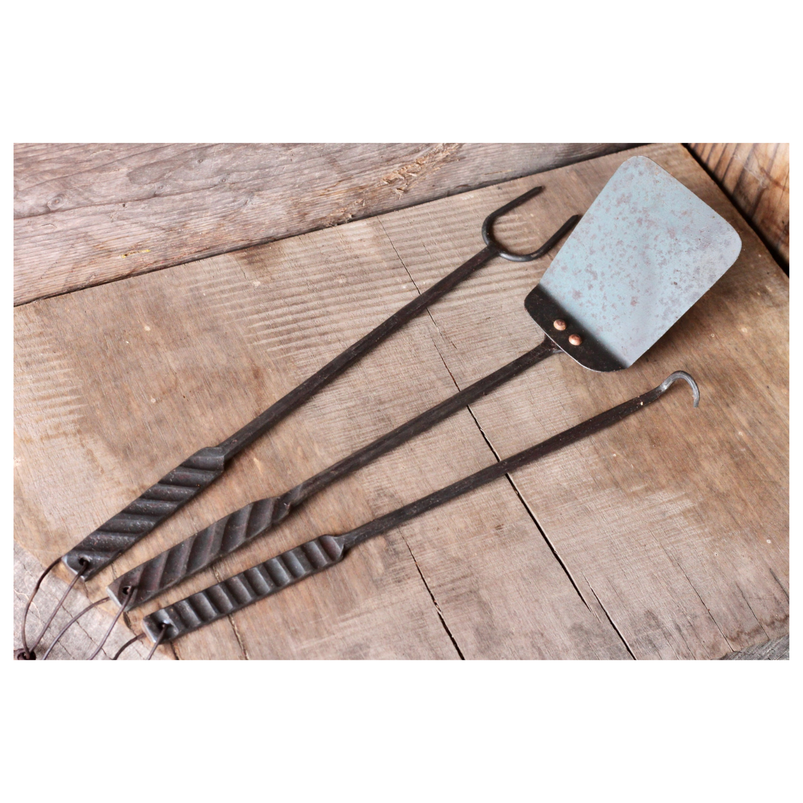 Three rustic kitchen utensils on a wooden surface