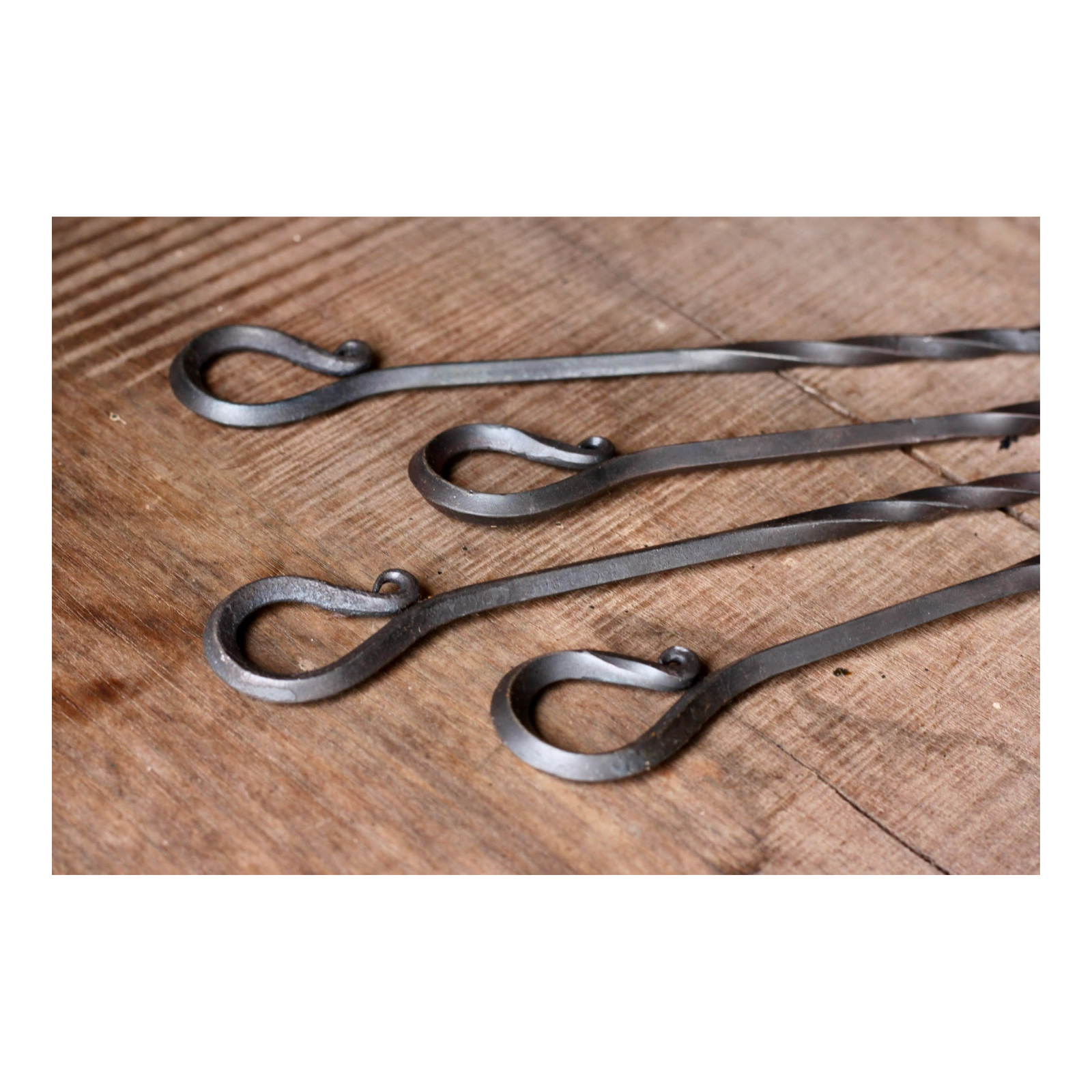 Three metal skewers on a wooden surface