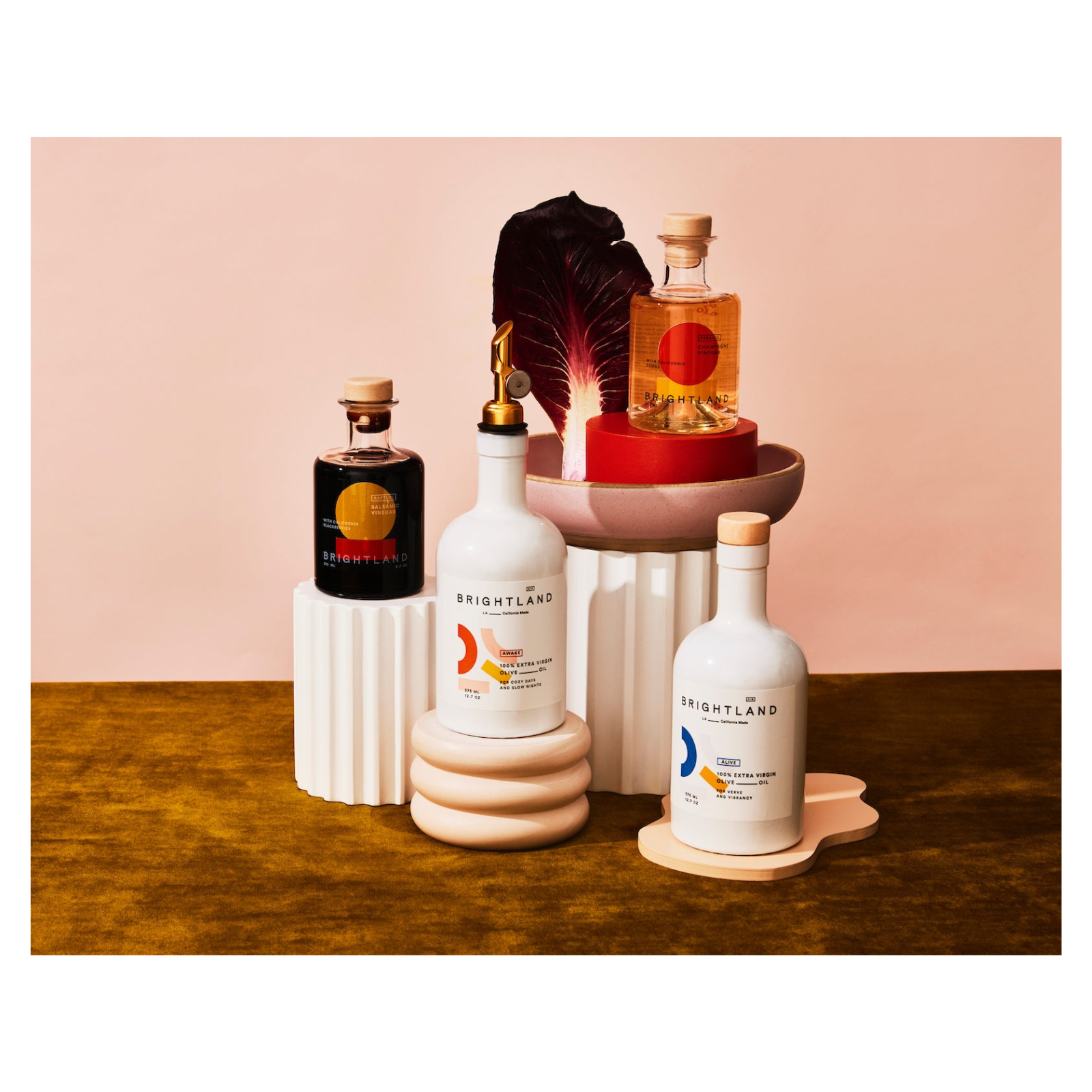 Collection of Brightland products on a wooden surface with a pink background