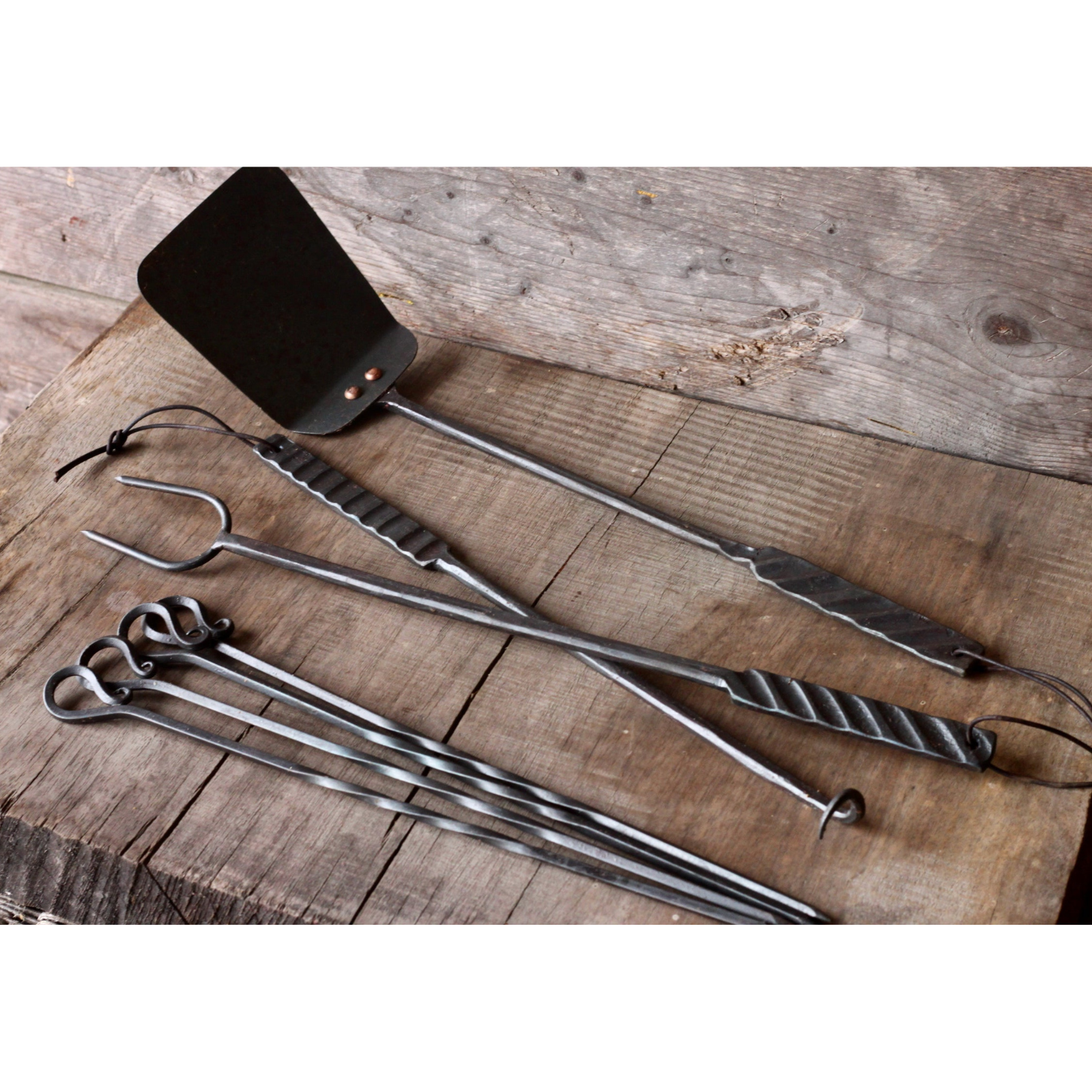 Set of metal barbecue tools on a wooden surface