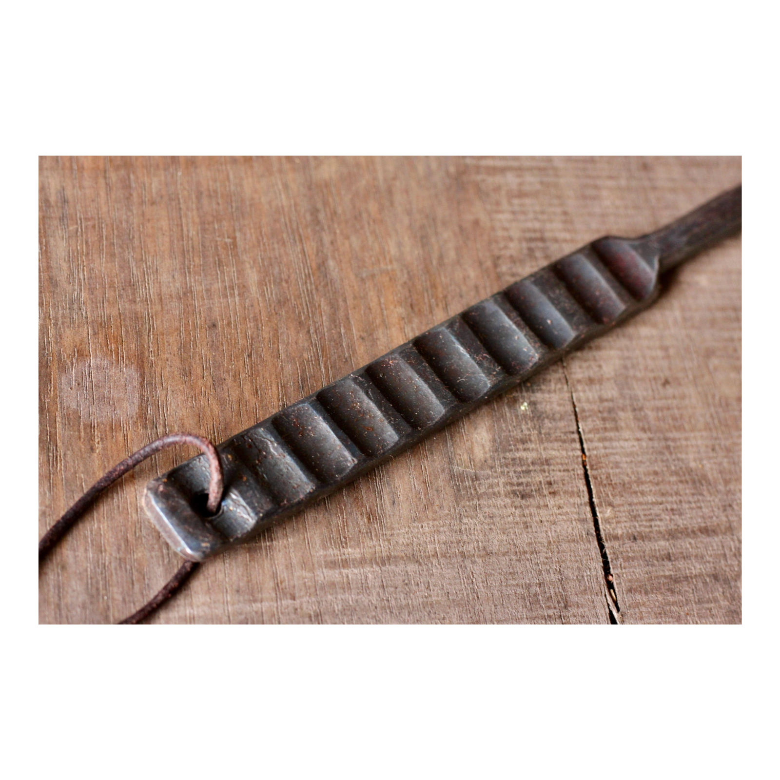 Decorative metal strip with a leather strap on a wooden surface