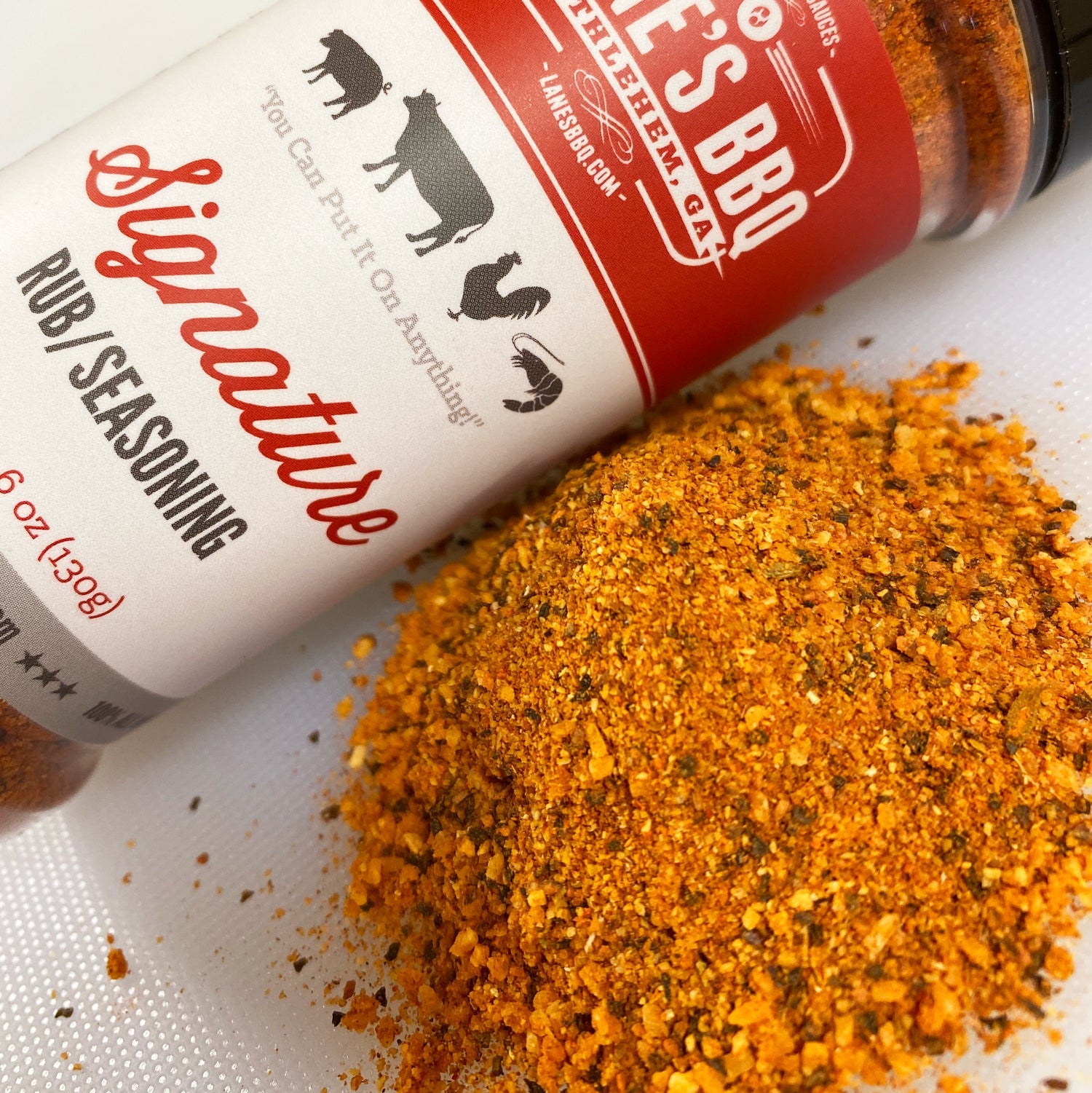 Lowe's BBQ seasoning bottle with spilled seasoning on a white surface