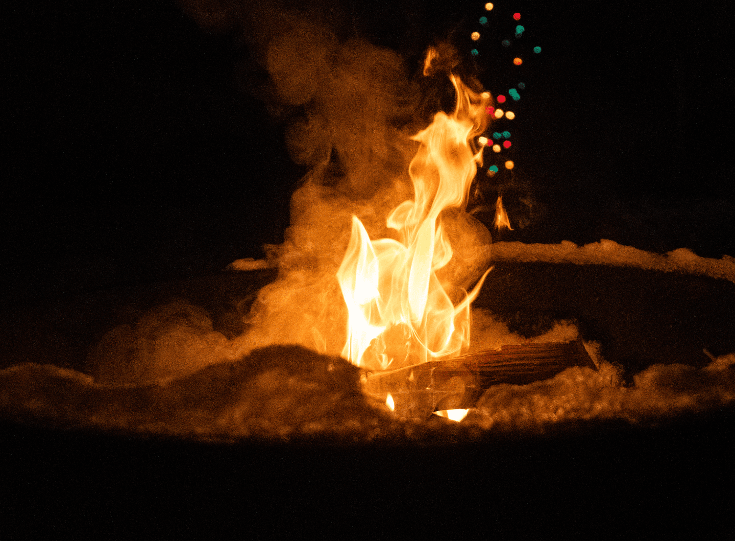a fire pit smoking against a dark sky with big bright flame and smoke 