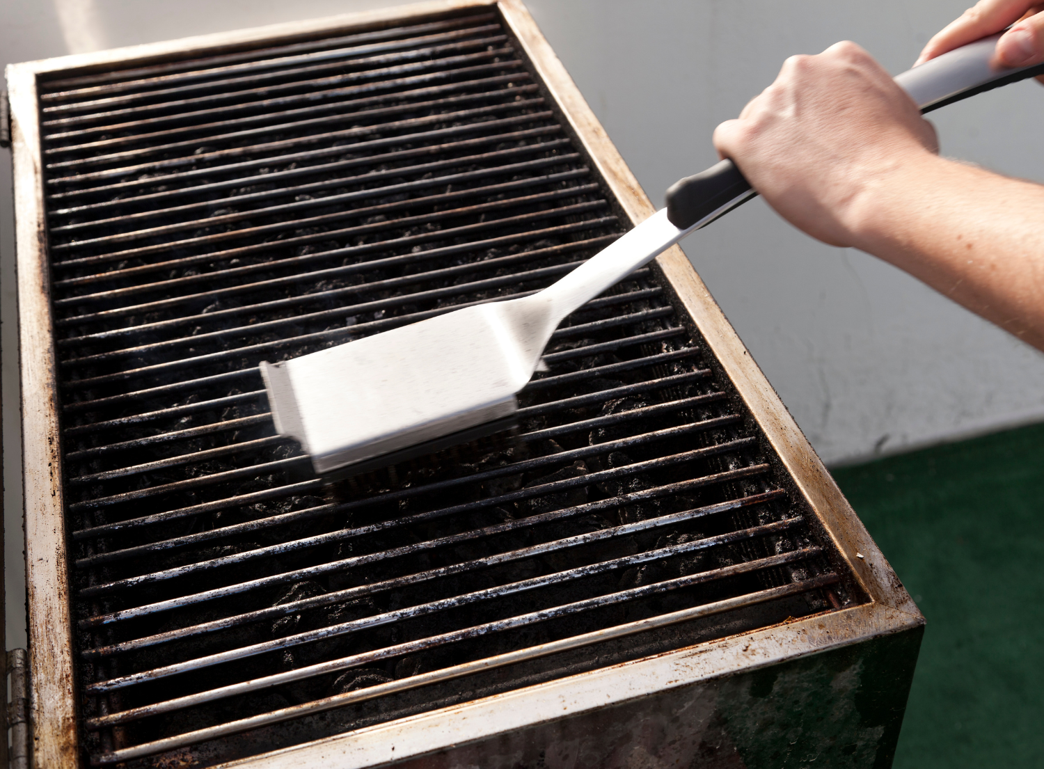 a dirty grill being cleaned with a metal scrubbing brush