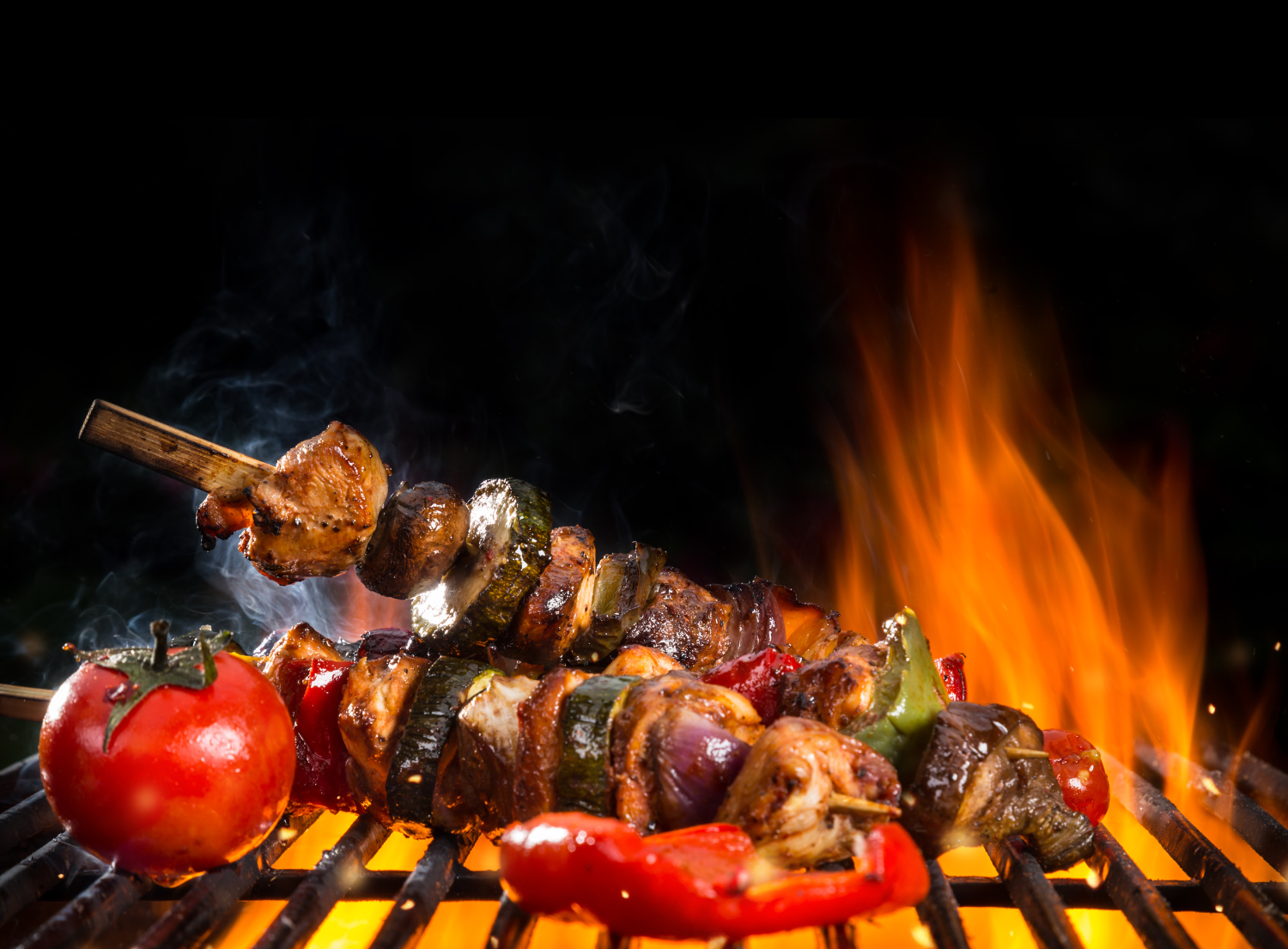 Beef kabobs grilling on bbq with tomato