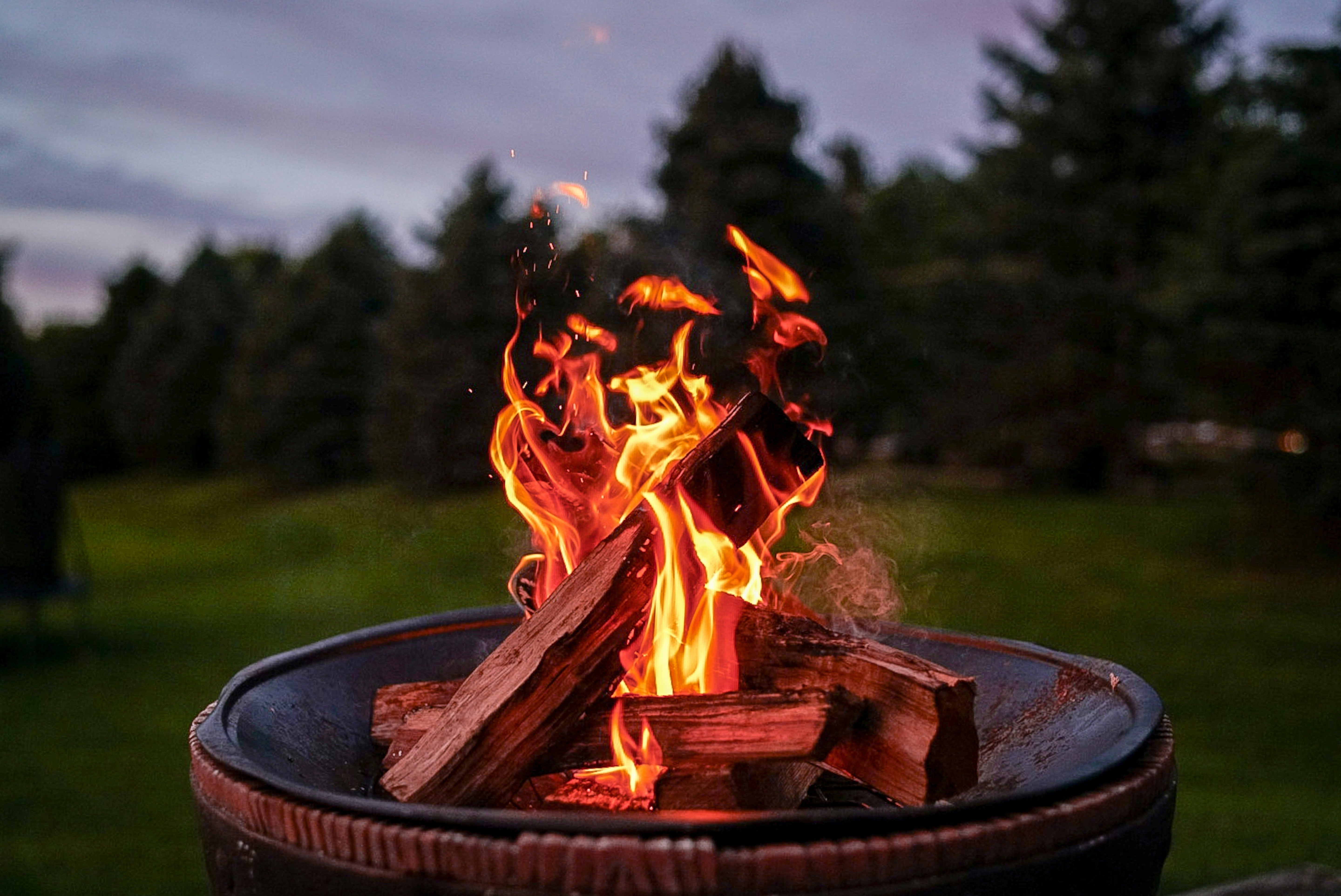 a lit fire pit in the middle of a open green space