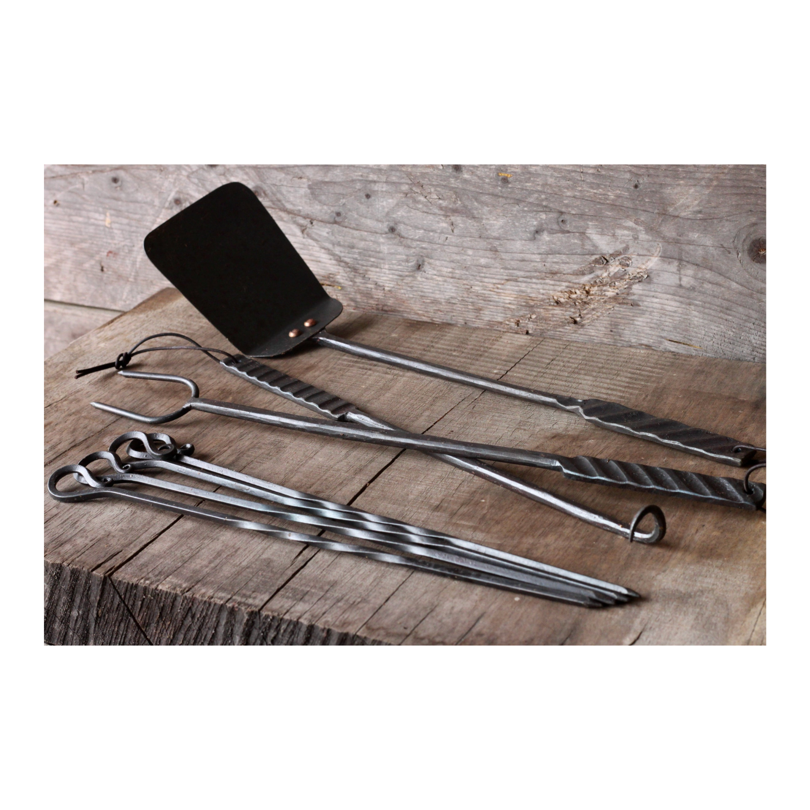Set of metal barbecue tools on a wooden surface