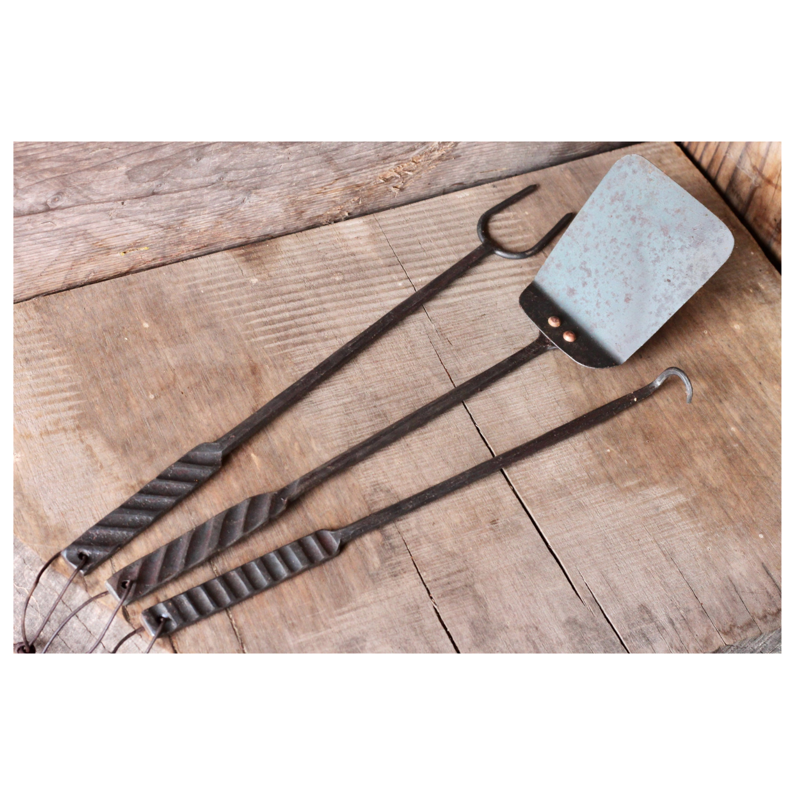 Three rustic kitchen utensils on a wooden surface