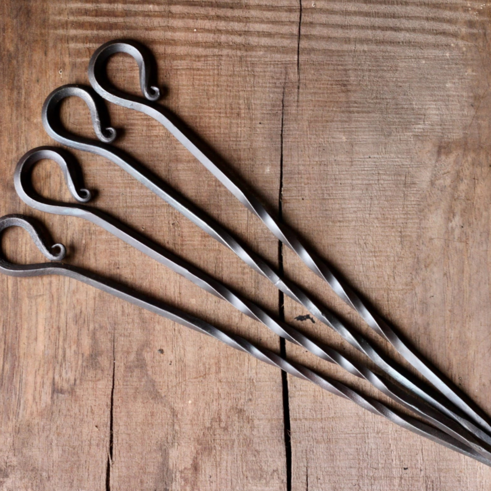4 metal skewers on a wooden table