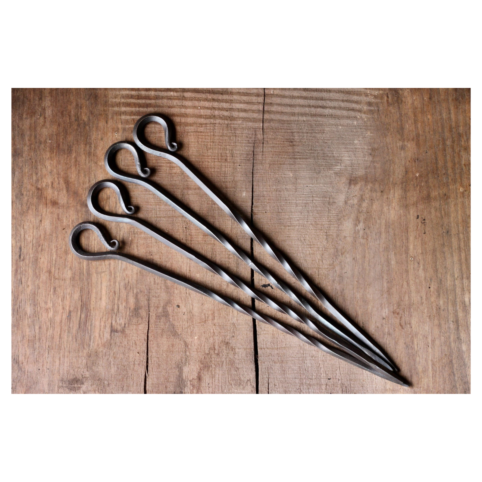 4 metal skewers on a wooden table