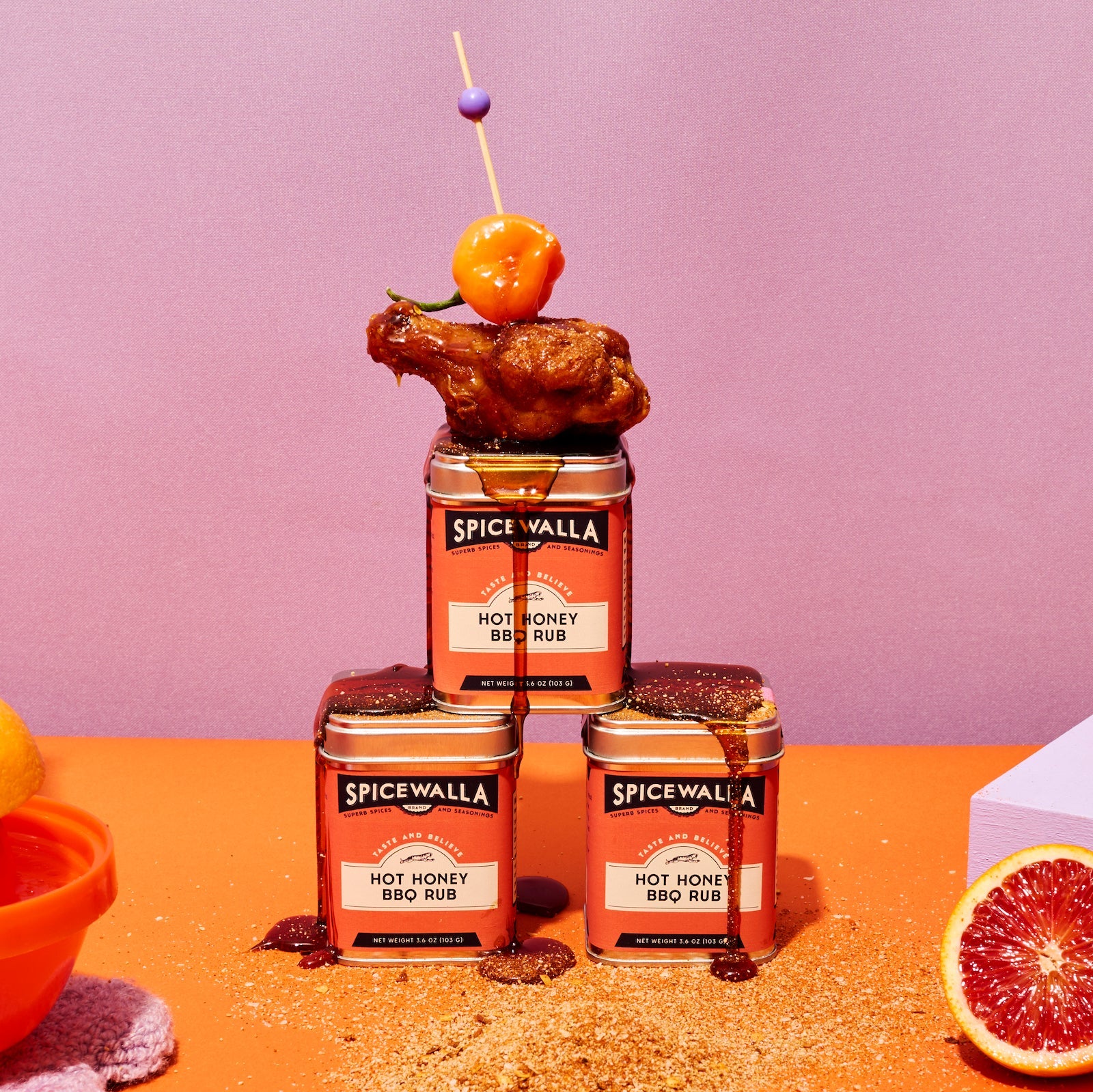 Spicewalla hot honey BBQ rub with a chicken skewer on a pink background