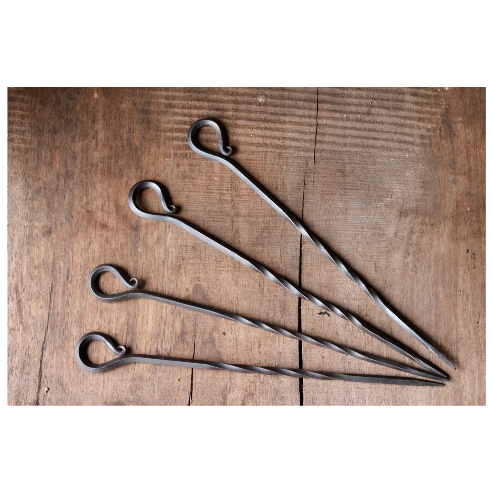 Four metal skewers on a wooden surface