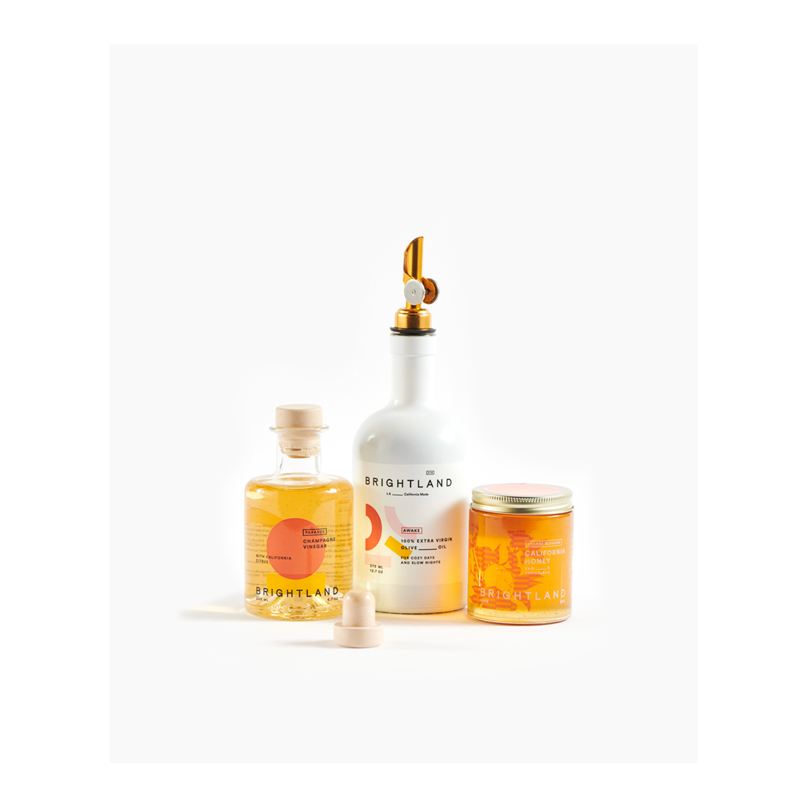 Collection of Brightland products including a bottle, jar, and dispenser on a white background