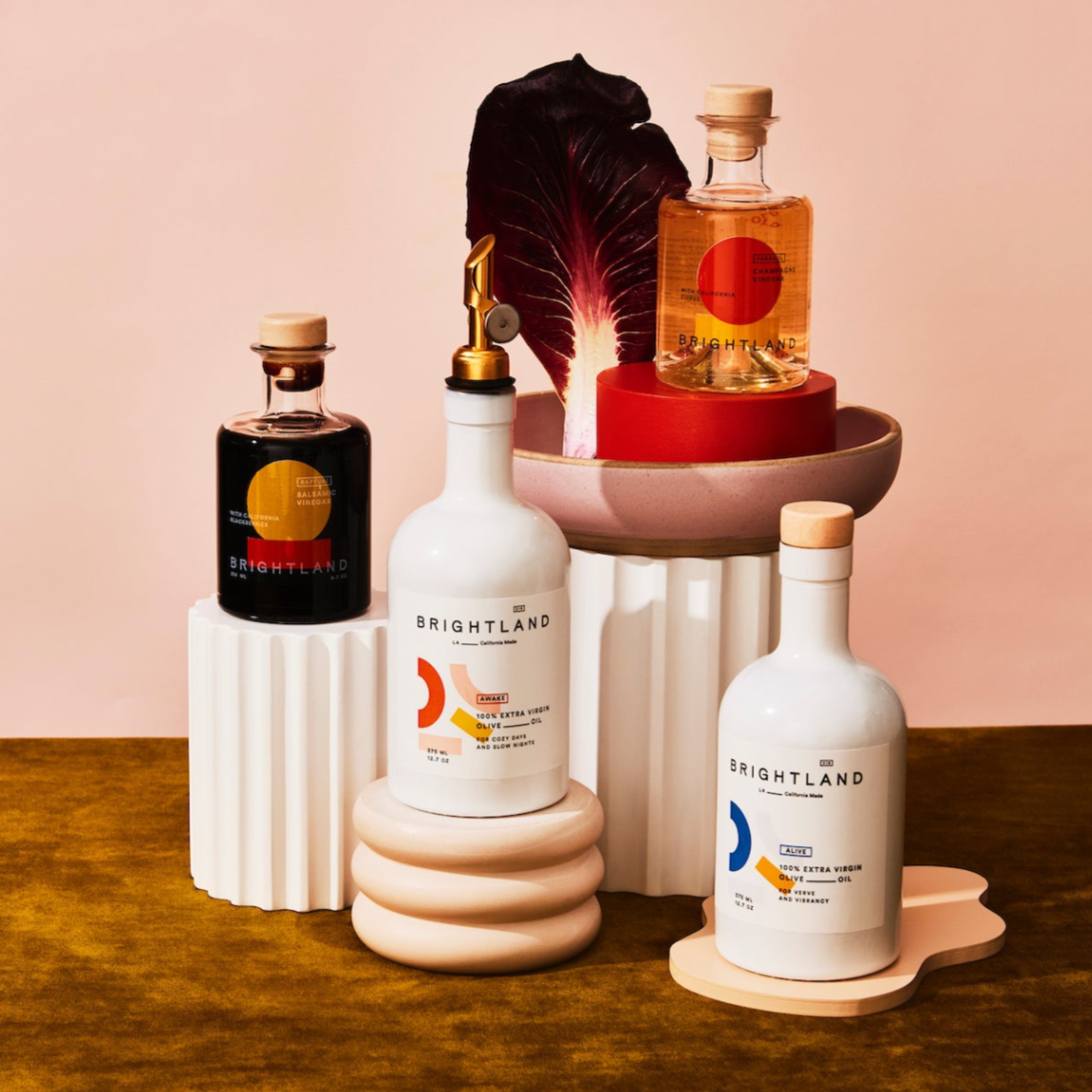 Collection of Brightland products on a wooden surface with a pink background
