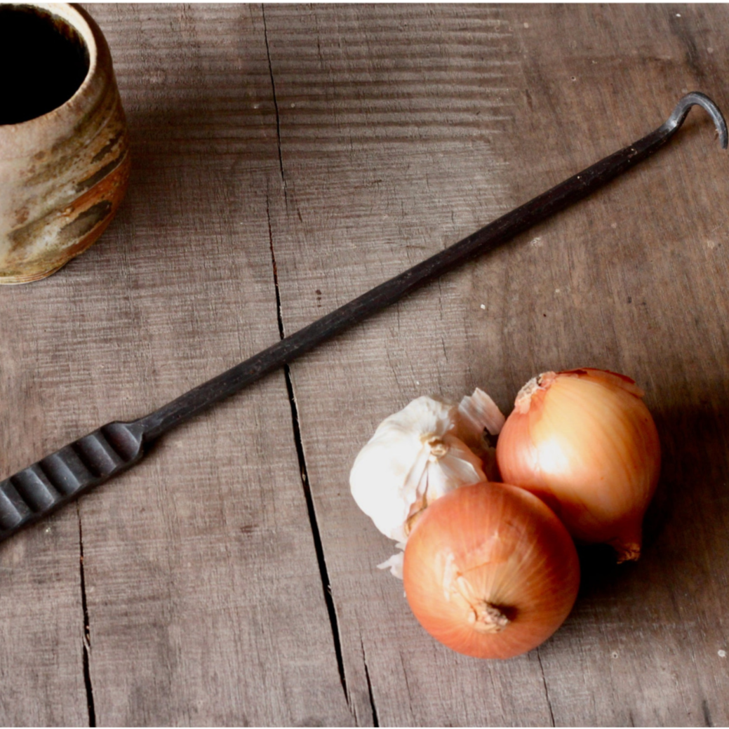 Vintage-style metal tool, onions, and garlic on a wooden surface