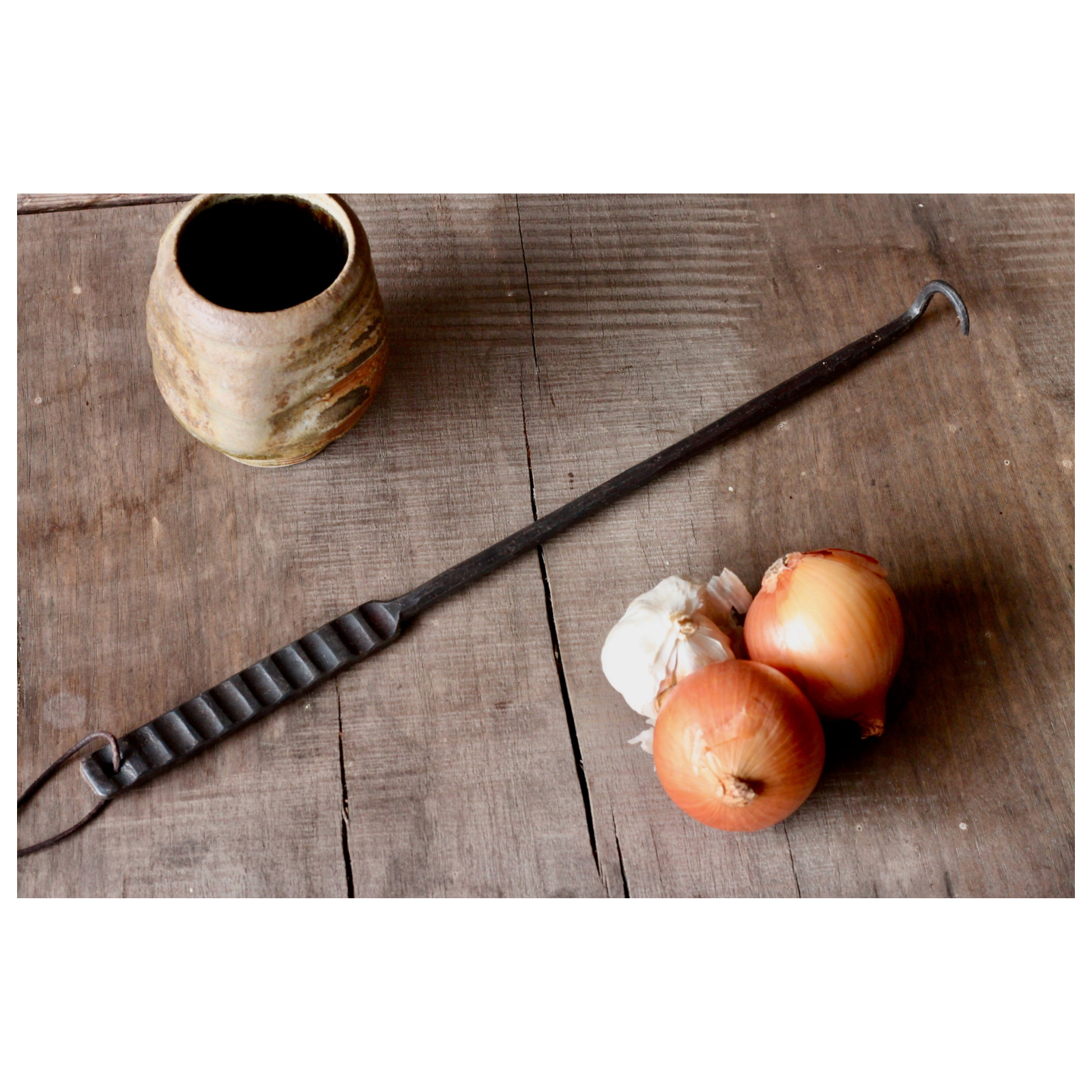 Vintage-style metal tool, onions, and garlic on a wooden surface