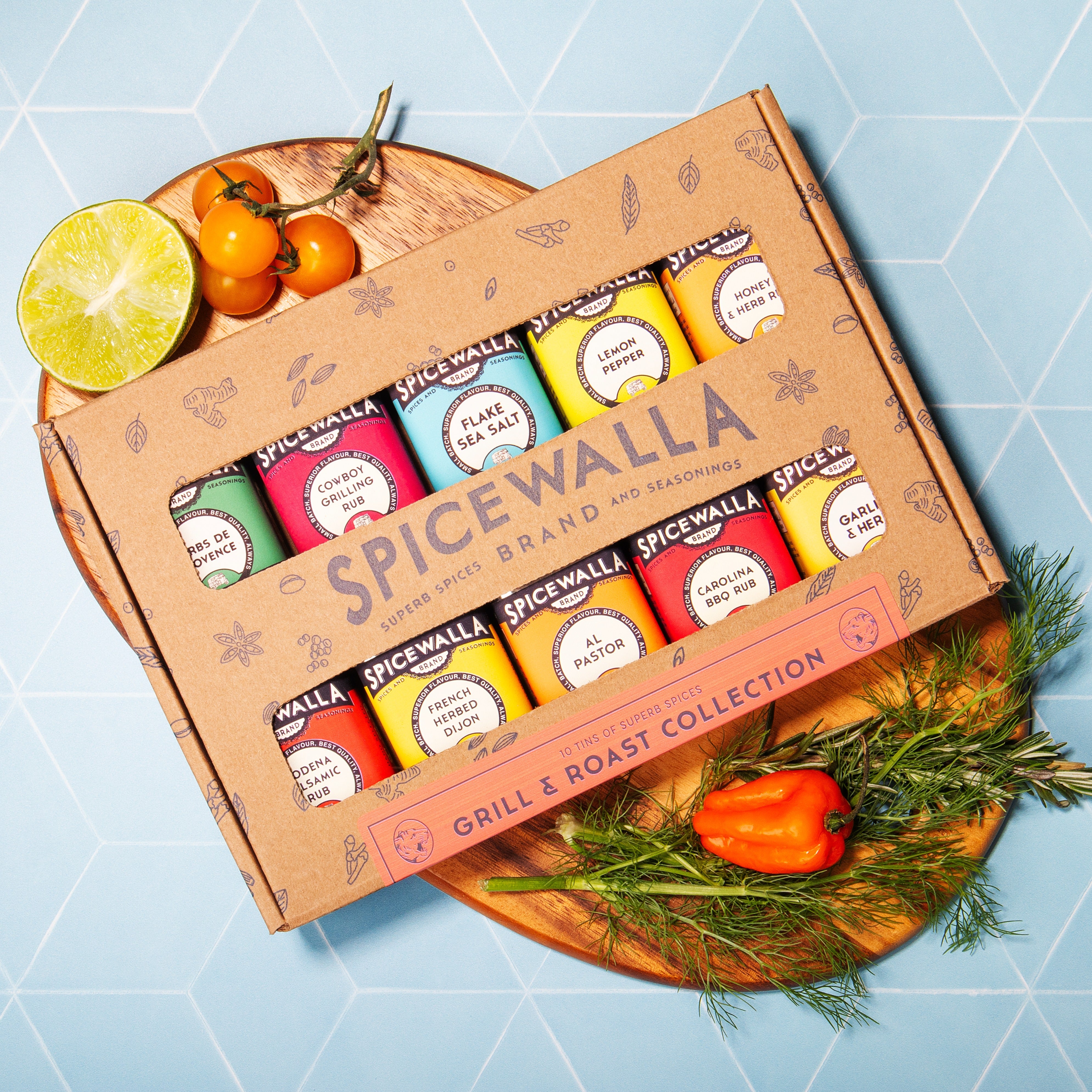 Spicewalla seasoning collection on a wooden board with vegetables on a blue tiled background