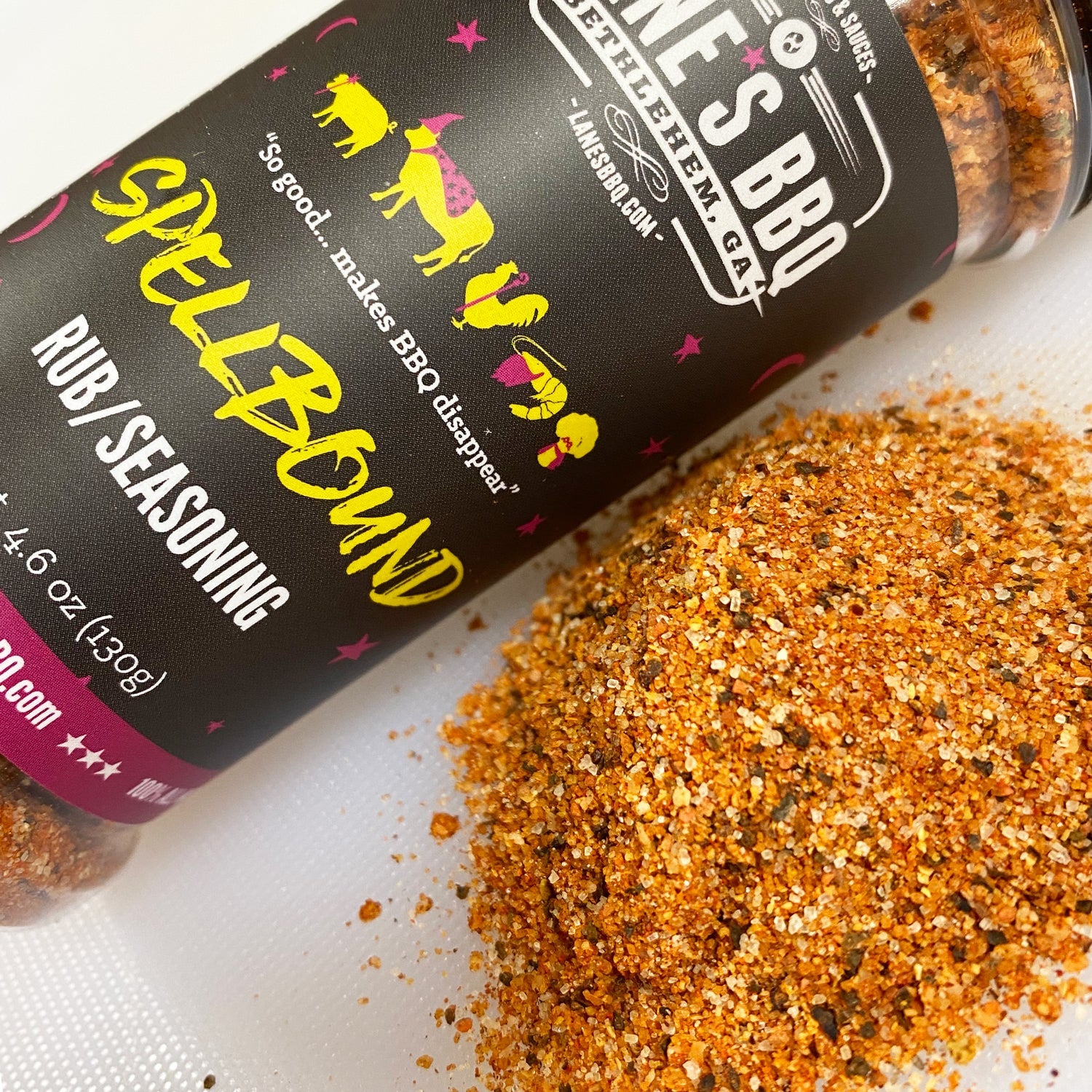 Bottle of Laine's BBQ Spellbound Rub/Seasoning with spilled seasoning on a white surface